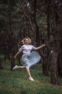 Full length of woman jumping in forest