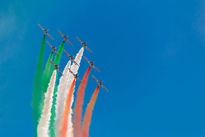 Low angle view of airshow against clear blue sky