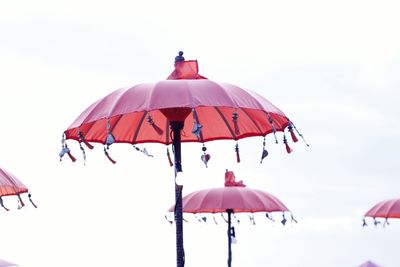 Low angle view of red flag against overexposed sky