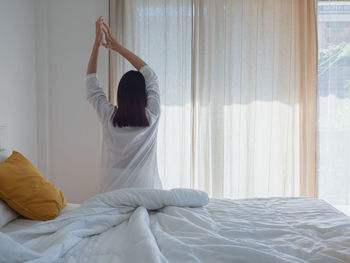Midsection of woman relaxing on bed at home