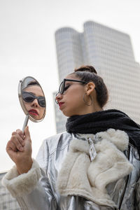 Woman holding mirror in city