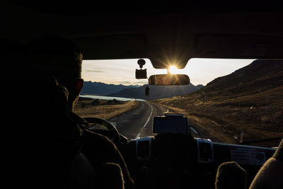 Rear view of man standing on road at sunset