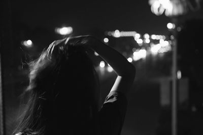 Woman with hand in hair outdoors at night