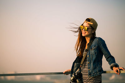 Young woman standing by sea against clear sky