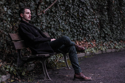 Side view of young man sitting on bench