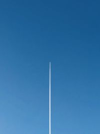 Low angle view of vapor trail against clear blue sky