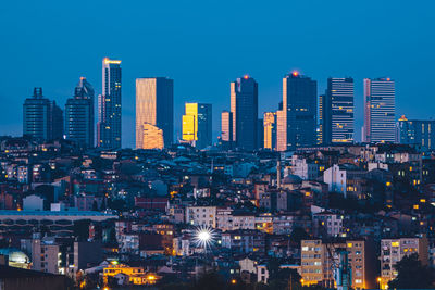 Illuminated modern buildings in city against sky