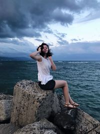 Full length of man on rock at sea shore against sky