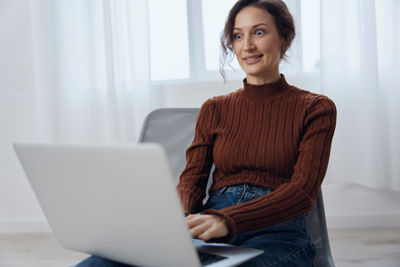 Portrait of young woman using laptop at home