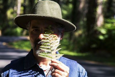 Earth day and love for nature concept with attractive man with a fern leaf covering one eye 