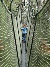 Rear view of girl walking on rope bridge