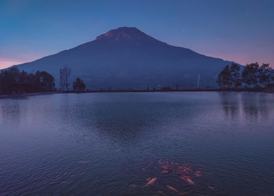 Scenic view of lake and mountains against sky at dusk