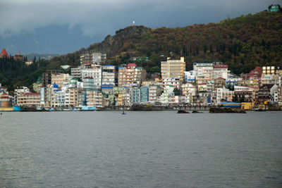 Sea by buildings in town against sky