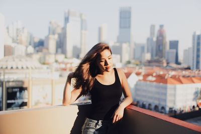 Beautiful young woman standing against cityscape