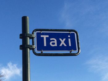 Low angle view of taxi sign against blue sky