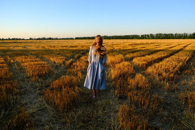 Woman standing on field against clear sky