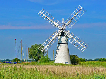 Traditional windmill on field against blue sky