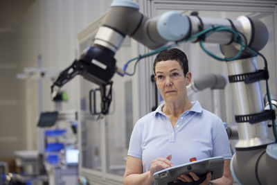 Focused mature technician examining robotic arm