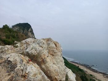 Rock formation on beach against sky