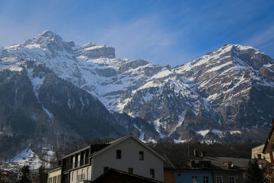 Panoramic view of buildings and snowcapped mountains against sky