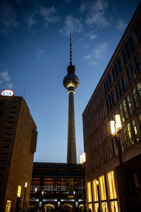 Low angle view of communications tower in city at night