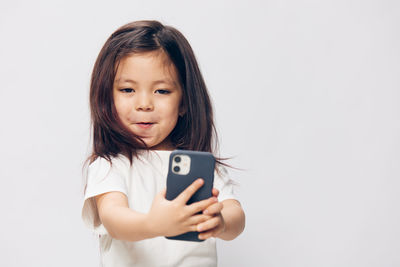 Portrait of young woman using mobile phone against white background