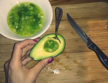 Cropped image of person holding fruit on table