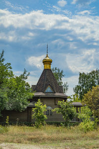 A christian temple made of a wooden frame with a golden dome and a cross. 