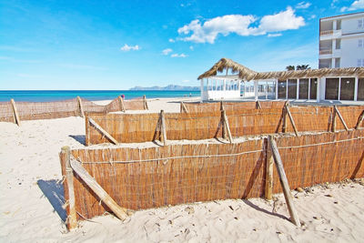 Deck chairs on beach against sky