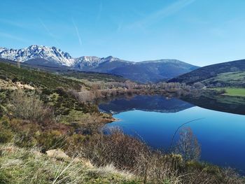 Scenic view of lake by mountains against sky