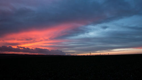 Scenic view of silhouette field against sky at sunset