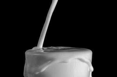 Close-up of pouring milk over black background