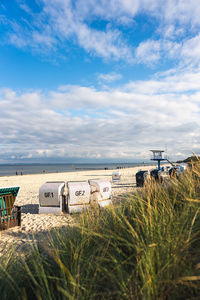 Hooded chairs on beach against sky