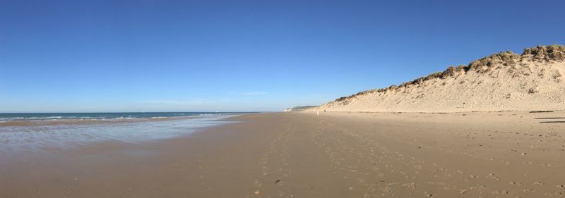 Scenic view of beach against clear blue sky