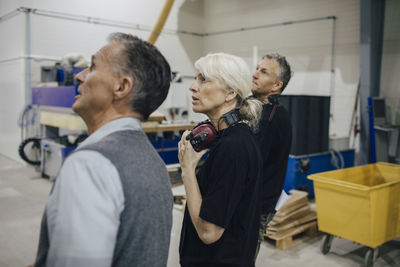 Business people discussing with colleagues while walking in industry