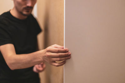 A young man is holding a white board from a closet.