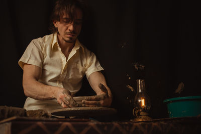 Man in pottery workshop makes plate of clay, an authentic atmosphere, yellow lamp, lifestyle, 