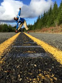 Man exercising on road against sky