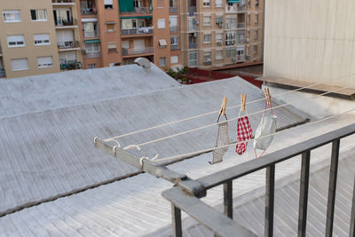 From above of various washed face masks hanging on laundry rope on balcony in city district