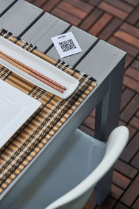 From above of piece of paper with qr code of menu placed on table with chopsticks and plate in asian restaurant