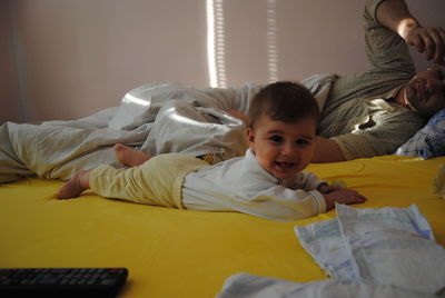 Portrait of cute baby boy with father lying on bed at home