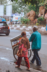 Rear view of people with umbrella on road