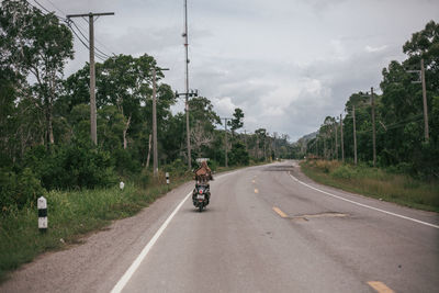 Man riding motorcycle on road against sky