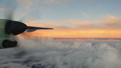 Airplane flying over cloudscape during sunset