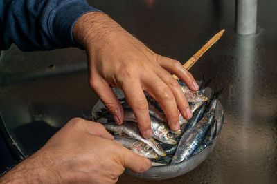 Cropped hand of man holding fishes in bowl