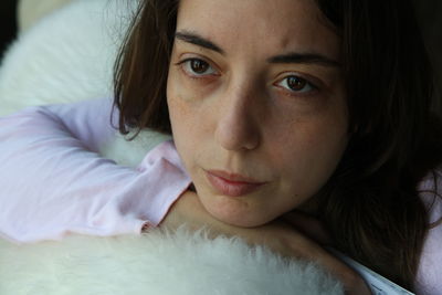 Close-up portrait of beautiful young woman lying on bed