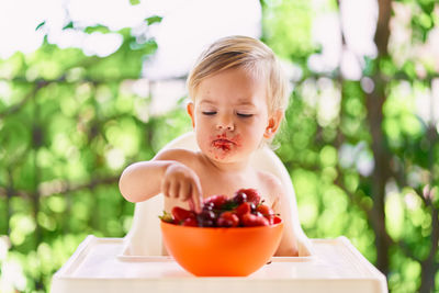 Baby girl sitting while eating strawberry at home