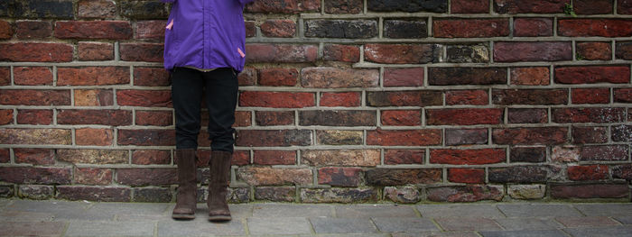 Low section of man standing against brick wall