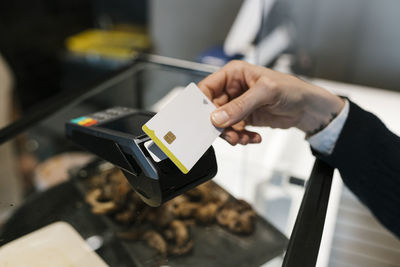 Female customer making payment through credit card in illuminated restaurant