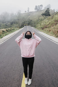 Portrait of woman wearing mask standing on road